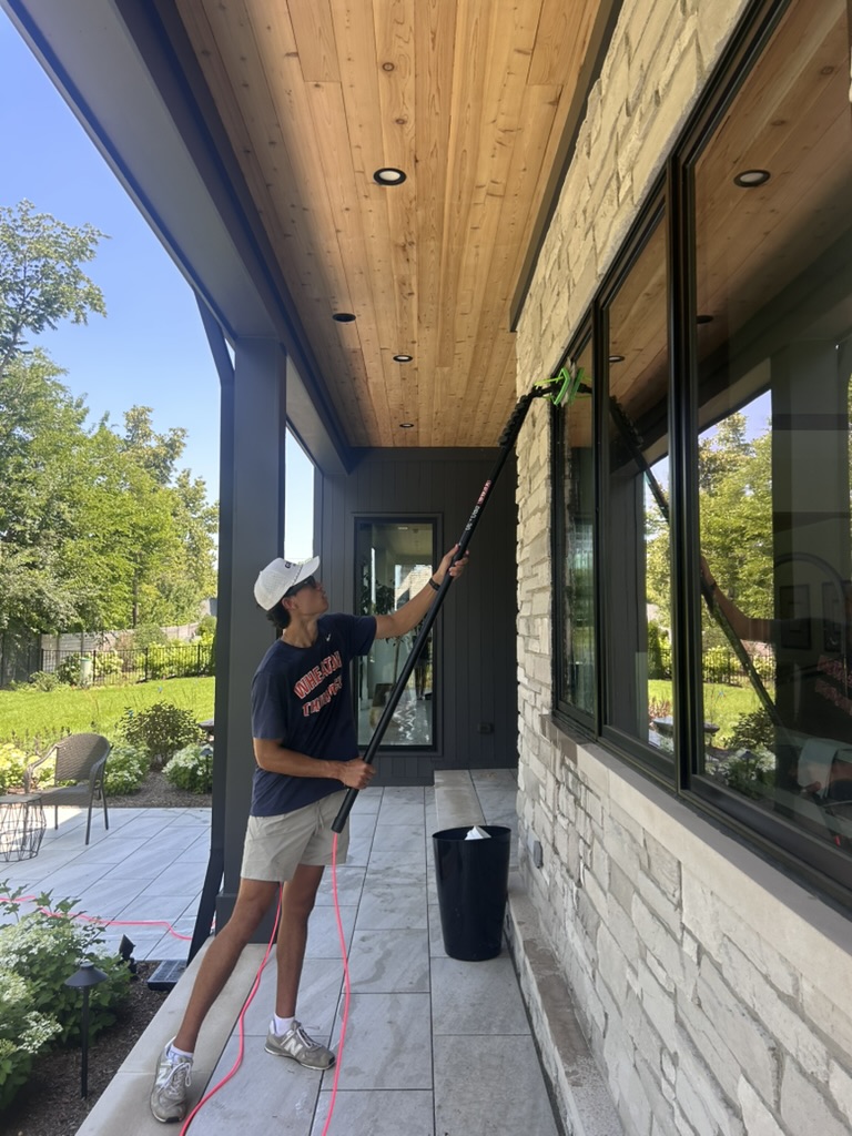 Team member cleaning tall porch windows with a waterfed pole