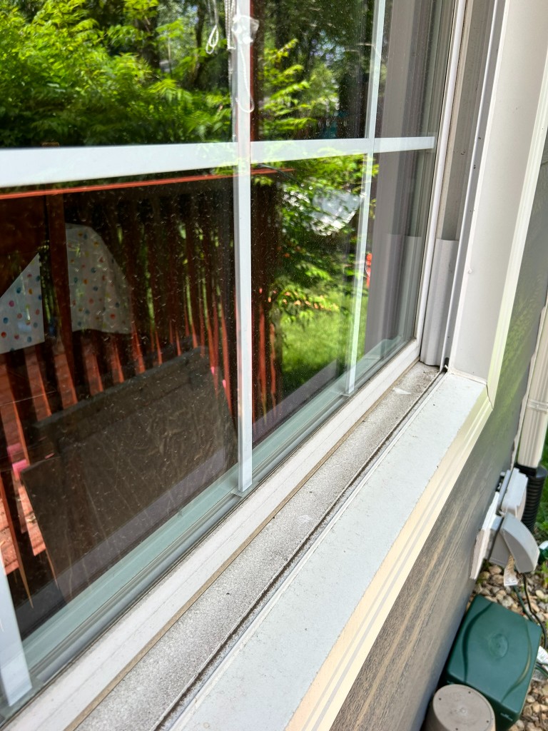 Exterior window with dust and grime on glass and tracks before cleaning